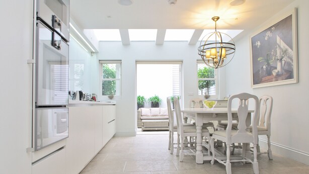 A bright kitchen with white cabinets, a dining table with chairs, and a chandelier. - Elegant Chelsea Townhouse On Quaint Street (London)