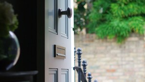 A door with a handle and a lock, a small window, and a metal gate with a ball finial. - Elegant Chelsea Townhouse On Quaint Street (London)