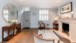 A spacious living room with hardwood flooring, a large mirror, a fireplace, and a comfortable seating area. - Elegant Chelsea Townhouse On Quaint Street (London)
