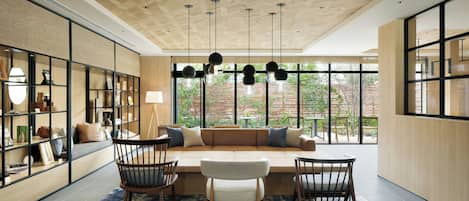 Un interior moderno con techo de madera, un área de estar central con sofá y sillones, y un amplio ventanal con vistas al exterior.
