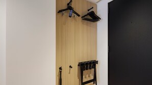 Un armario de madera con una puerta negra, un perchero negro y un perchero de pared negro.