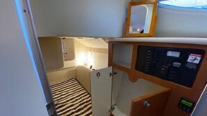 A compact cabin with a bed, a small bathroom, and a control panel.
