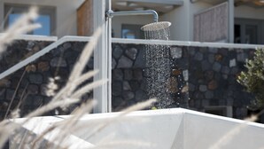 A modern outdoor shower with a stone wall backdrop.