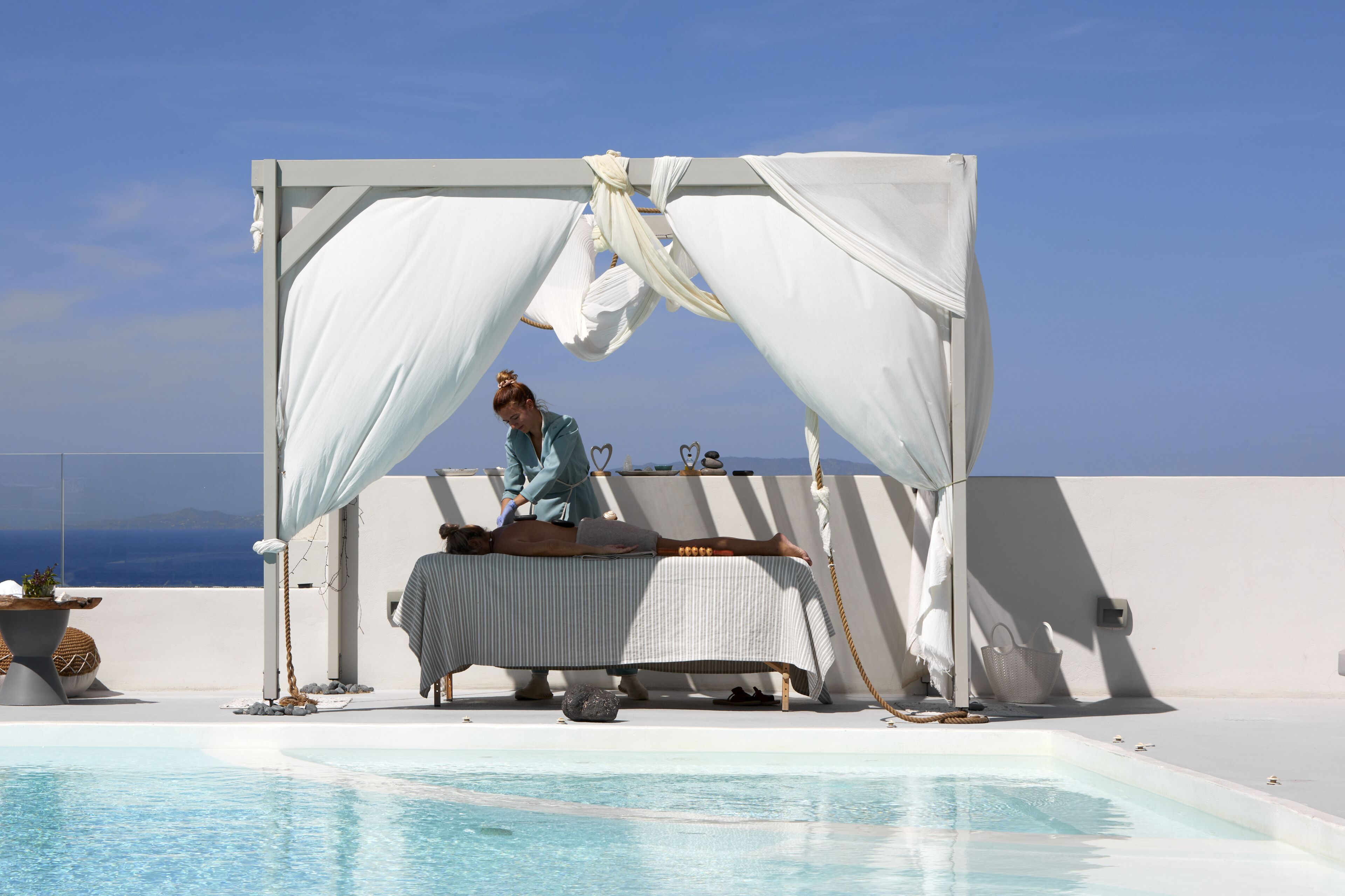 A spa setup with a massage table, a canopy, and a pool.