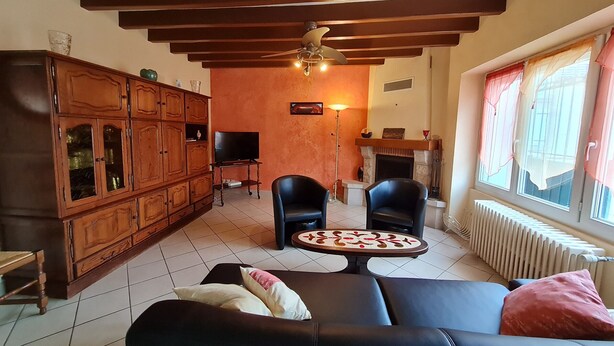 A living room with a sofa, two chairs, a television, a cabinet, a fireplace, and a window with curtains. - Renovated 4-Bedroom House near Loire Castles, Ideal for Families & Pros (Cléry-Saint-André)