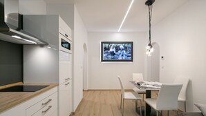 Una cucina moderna con mobili bianchi, un piano di lavoro in legno e un forno integrato.