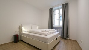 Camera singola con un letto, pavimento in legno, termosifone e finestra con tende.