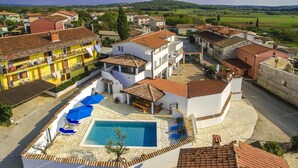 A residential area with a swimming pool surrounded by white buildings with red-tiled roofs. - Holiday home with a pool for 7 persons only 6 km from beautiful beaches. (Porec)