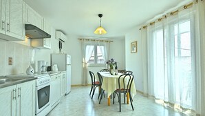 A spacious kitchen with white cabinetry, a dining table with chairs, and a large window with curtains. - Holiday home with a pool for 7 persons only 6 km from beautiful beaches. (Porec)