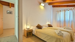 A bedroom with two beds, a nightstand with a lamp, wooden beams on the ceiling, and a window with curtains. - Holiday home with a pool for 7 persons only 6 km from beautiful beaches. (Porec)