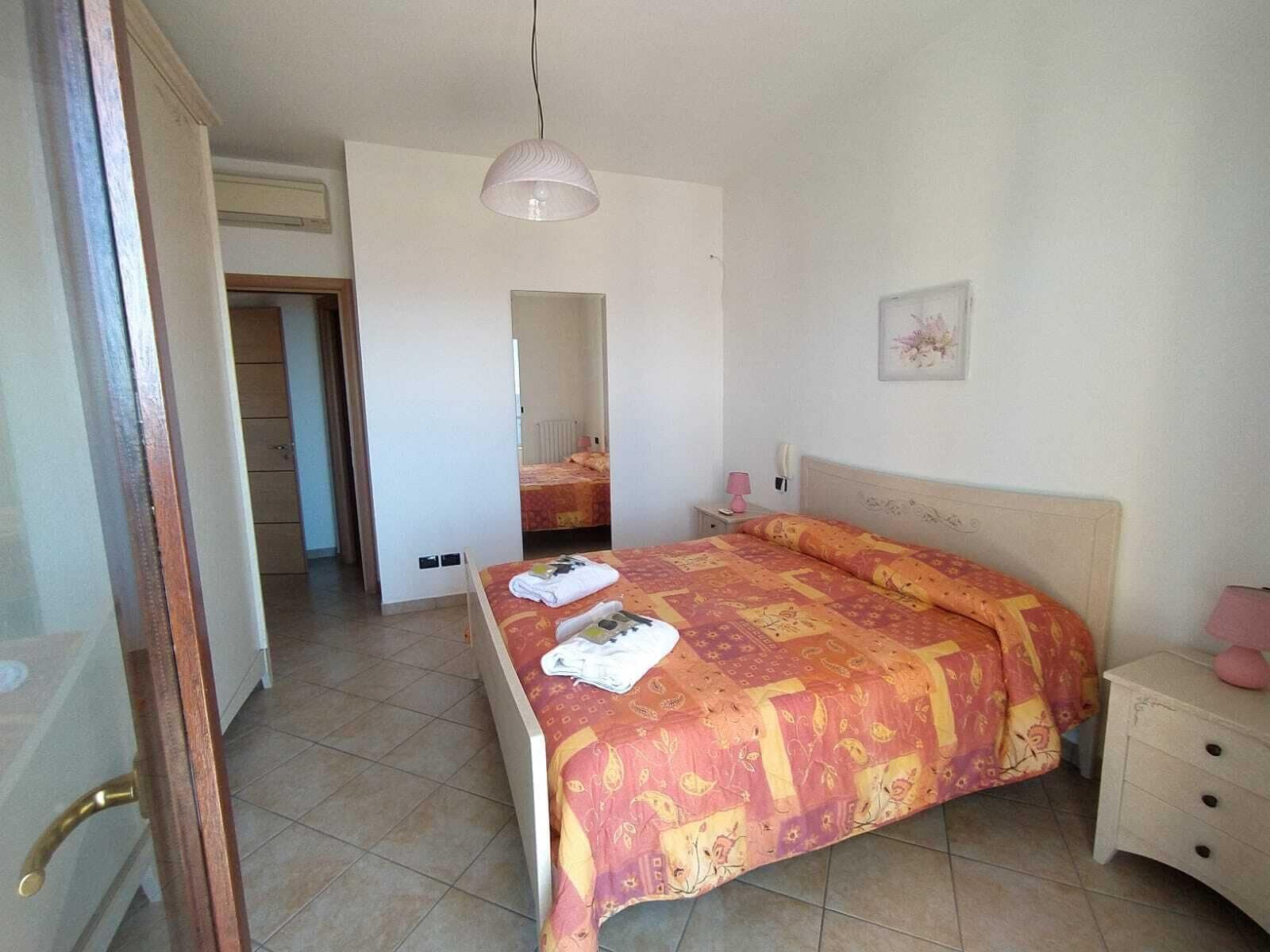 A bedroom with a bed, bedside table, and a hanging light fixture.