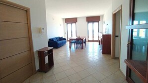 A spacious living area with a blue sofa, a dining table, and a kitchen area. - Rosa Virginia vista mare (Gallipoli)
