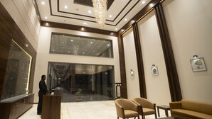 A modern lobby with a reception desk, seating area, and a staircase leading to upper floors. - Hotel Rajhans Abhinandan (Bhopal)