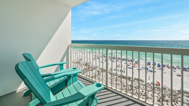 Ein Balkon mit Blick auf einen belebten Strand und das Meer.