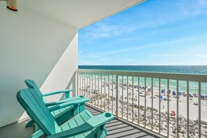A balcony with a view of a crowded beach and ocean.