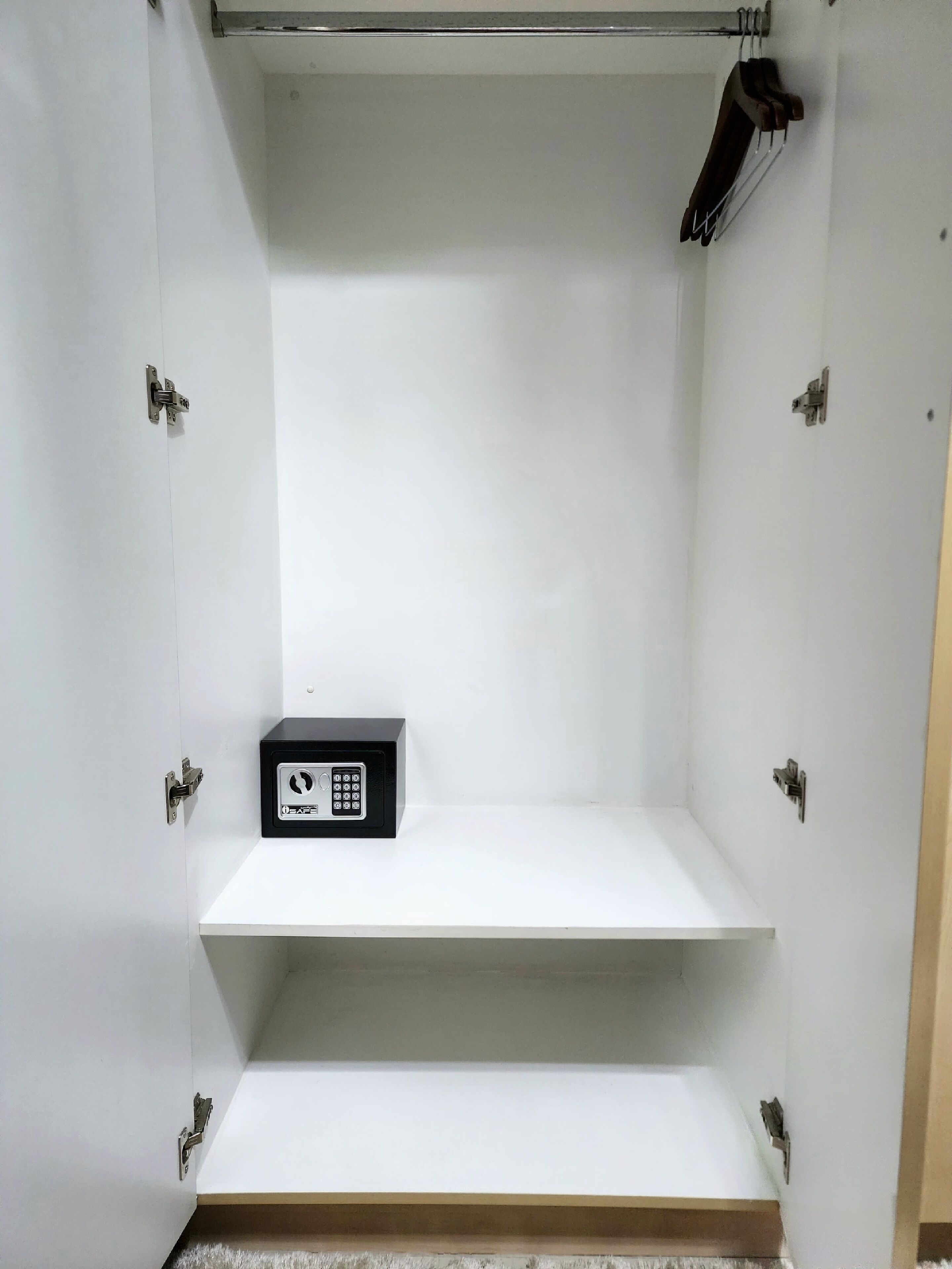 A room with a white door, a black electronic device on a shelf, and a coat hanging on the wall.