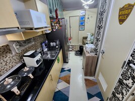 A compact kitchen with a microwave, coffee maker, and a refrigerator.