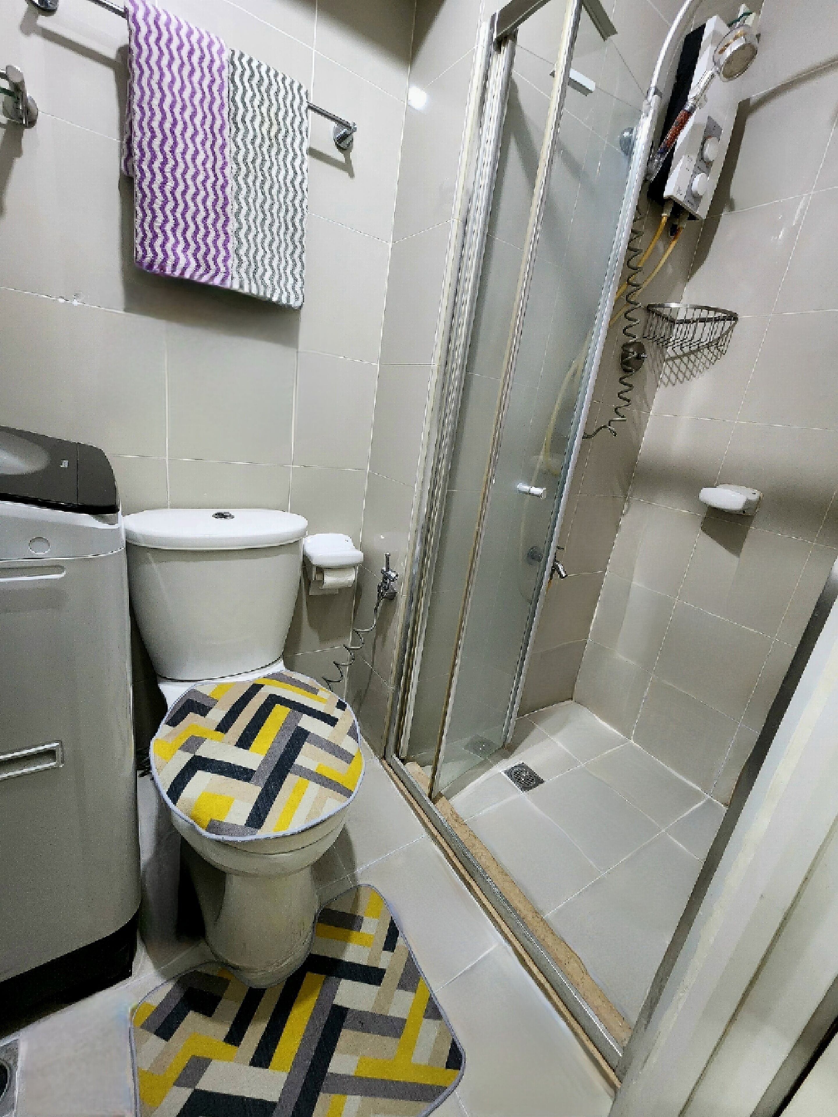 Un baño con inodoro, ducha y piso estampado.