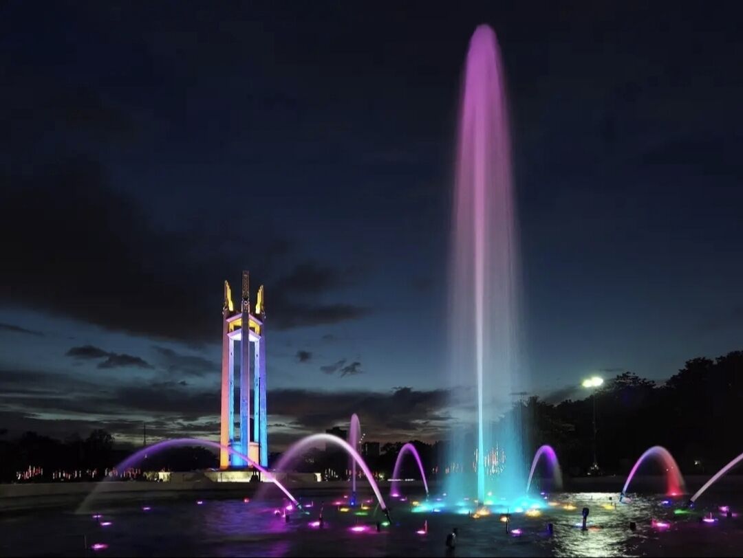 Una escena nocturna con un espectáculo de fuentes iluminado por luces de colores.