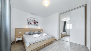 Una camera da letto moderna con un letto in legno, un comodino, un condizionatore d'aria a parete e un grande specchio.