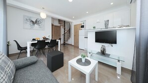 Un soggiorno moderno con un divano, un tavolino in vetro e una TV a parete.