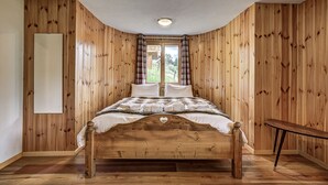 Una camera da letto con un letto di legno, una finestra con tende e un tavolino.