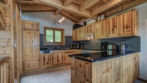 Una cucina in stile baita in legno con isola centrale, mobili a incasso, una finestra ed elettrodomestici essenziali.