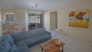 A living room with a grey sofa, a wooden coffee table with a vase of flowers, and a painting on the wall. - Apt. Suri, Modern 2BDR Apt. in the heart of Ayia Napa, Close to Nissi Avenue (Ayia Napa)