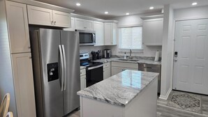 A modern kitchen with stainless steel appliances, white cabinetry, and a granite countertop. - Estero Sands Condo with 2 bedrooms and 2 baths (Fort Myers Beach)