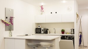 Une cuisine moderne avec des meubles blancs, un four à micro-ondes, une machine à café et un évier.