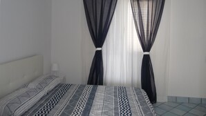 A bedroom with a bed, a nightstand, and sheer curtains. - GALATEA - One step away from the sea - LEMON. (Mascali)