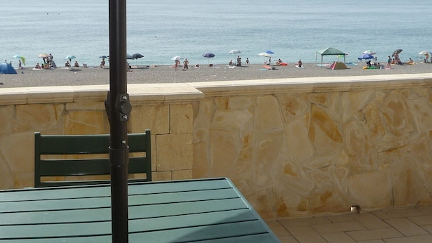 A beach view with a stone wall, a green table, and a metal chair. - GALATEA - One step away from the sea - LEMON. (Mascali)