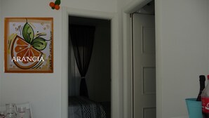 A hotel room with a bed, a table with glasses, a painting, and a door. - GALATEA - One step away from the sea - LEMON. (Mascali)