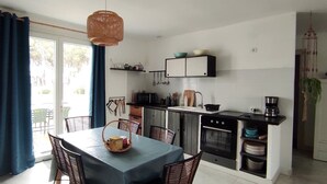 A compact kitchen with a dining area, featuring a table with chairs, a microwave, an oven, and a coffee machine. - Vacation home 3* LES MATHES/LA PALMYRE (Les Mathes)