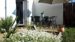 An outdoor patio with a table and chairs, surrounded by potted plants and a wooden fence. - Vacation home 3* LES MATHES/LA PALMYRE (Les Mathes)