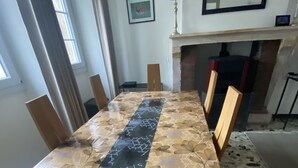 A dining table with a patterned tablecloth, surrounded by wooden chairs. - 3-bedroom house in the heart of the National Forest Park (Arc-en-Barrois)