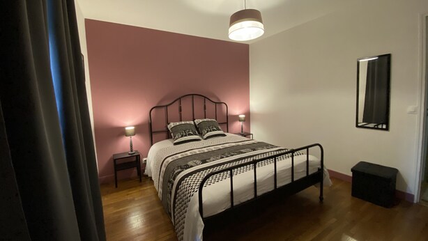 A bedroom with a bed, bedside lamps, a mirror, and a small stool. - 3-bedroom house in the heart of the National Forest Park (Arc-en-Barrois)