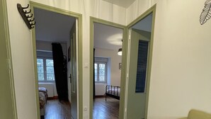 A room with a wooden floor, a green couch, and a door leading to another room. - 3-bedroom house in the heart of the National Forest Park (Arc-en-Barrois)