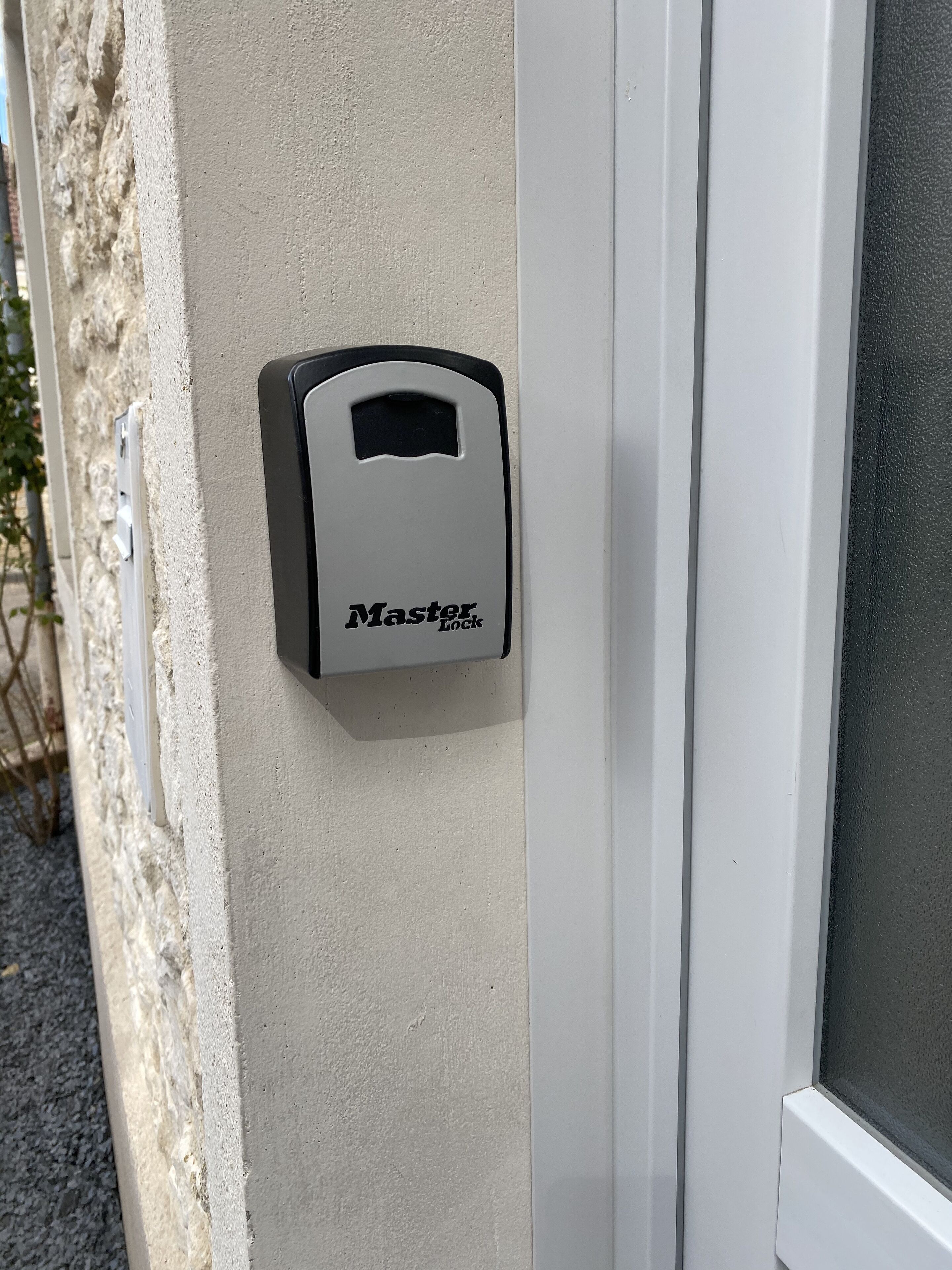 Un cadenas de la marque Master Lock est fixé sur un mur beige, près d’une porte blanche.
