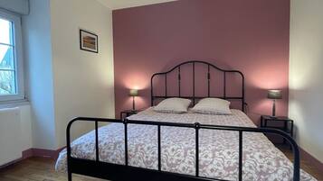Een slaapkamer met een bed, twee bedlampen, een raam en een plafondlamp.