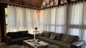 A living room with two sofas, a coffee table, and wicker ottomans.