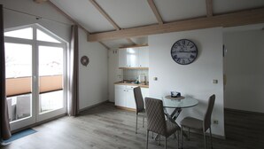 Uma cozinha moderna com armários brancos, teto de madeira e um espaço de refeições com mesa e cadeiras de vidro.