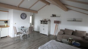 Um quarto amplo com área de jantar, sofá, cama e um relógio na parede.