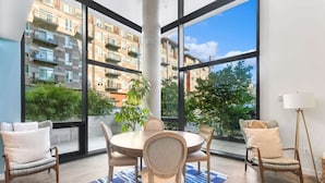 A modern apartment with a large window, a round dining table, and four chairs. - Elegant design meets optimal location amid the natural beauty of Downtown Redmond. (Redmond)