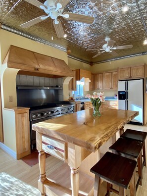 A kitchen with wooden cabinets, a central island, a stove, and a ceiling fan. - Spacious Historic Home in the White Mountains, great for Groups, Sleeps 14 (Bartlett)
