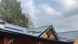 Une cabane en bois dotée d’un porche couvert et d’une terrasse délimitée par une clôture.