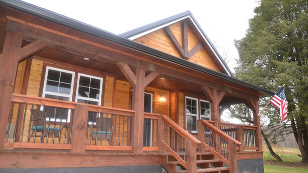 Une cabane en bois avec une véranda, un escalier et un drapeau.