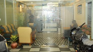 A reception area with a checkered floor, a reception desk, and a motorcycle parked outside. -  TNV Residency (Puducherry)