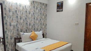 A neatly made bed with a white mattress, a yellow throw blanket, and a wooden headboard. -  TNV Residency (Puducherry)
