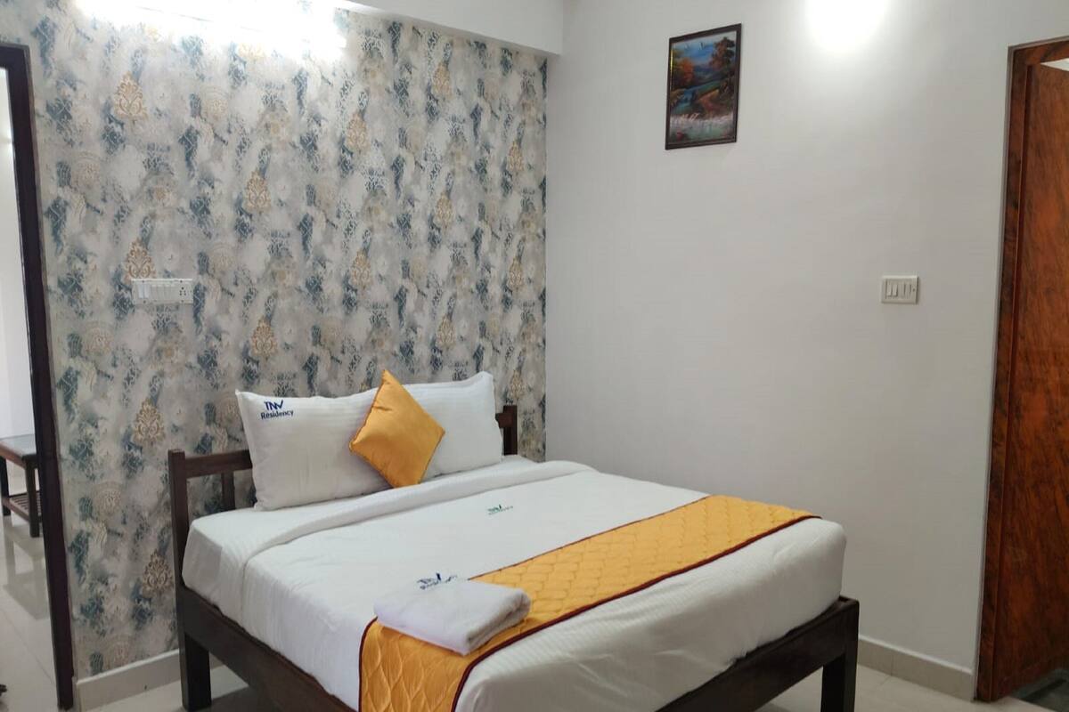 A neatly made bed with a white mattress, a yellow throw blanket, and a wooden headboard.